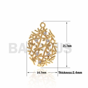 Puede incluir: Pendiente de tono dorado con un delicado diseño de ramas entrelazadas con pequeñas piedras transparentes. El pendiente mide 14,7 mm de ancho y 21,7 mm de alto.