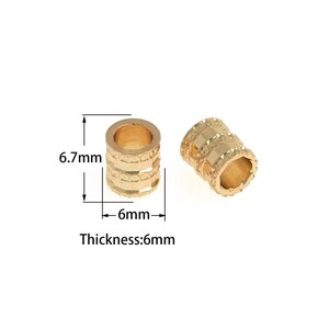 May include: Two gold-colored metal beads with a decorative pattern. The beads are 6.7 mm in diameter and 6 mm thick.