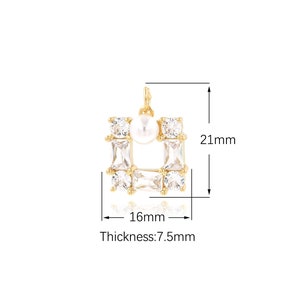 May include: Gold-tone pendant charm featuring a square frame with clear cubic zirconia stones and a white pearl in the center. The pendant measures 16 mm wide and 21 mm tall, with a thickness of 7.5 mm.