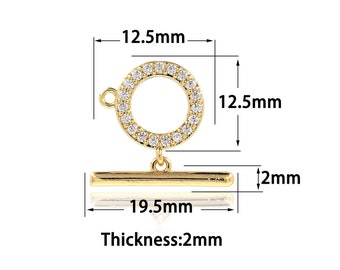 May include: Gold-tone toggle clasp with a round, clear crystal-encrusted ring and a straight bar. The ring measures 12.5 mm in diameter and the bar is 19.5 mm long. The clasp is 2 mm thick.