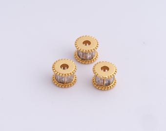 May include: Three gold-colored, cylindrical beads with a central band of clear, rectangular stones. The top and bottom of each bead have a circular design with a small hole in the center and a beaded edge. The beads are displayed on a white background.