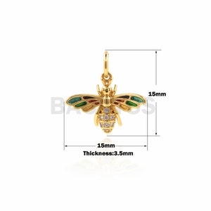 May include: Gold bee charm with green, red, and yellow enamel and clear cubic zirconia stones. The charm is 1.5 inches wide and 0.14 inches thick.