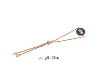 Puede incluir: Un brazalete ajustable de oro rosa con un dije de flor de loto azul y dorado. El brazalete mide 12 cm de largo. Longitud: 12 cm