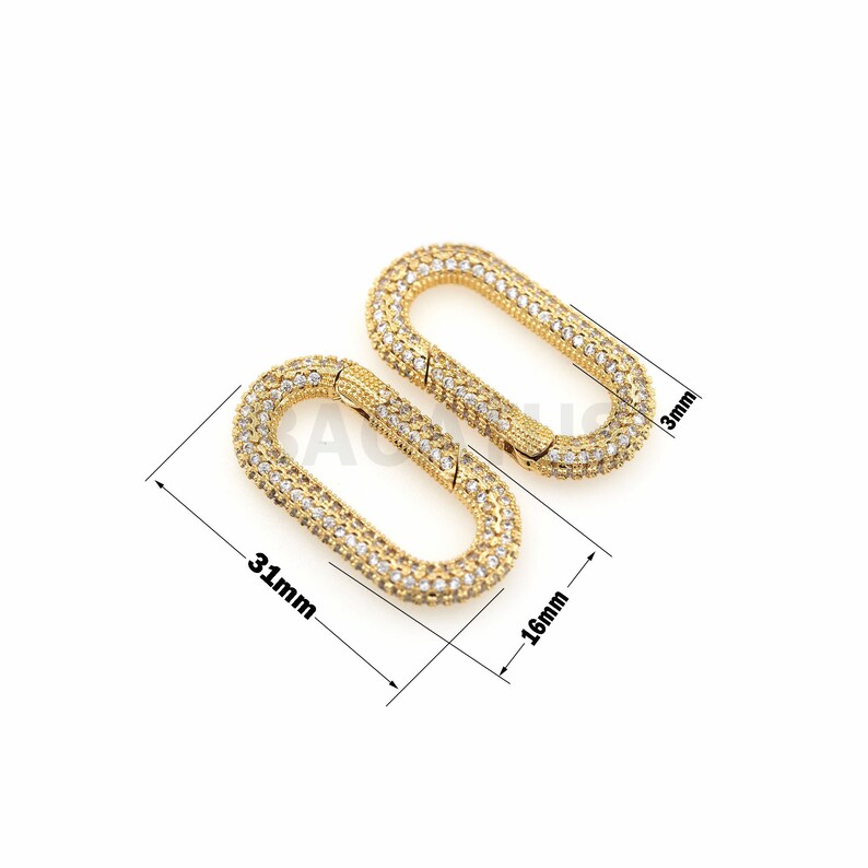 May include: Two gold-toned oval-shaped clasps with clear rhinestones. The clasps are 31 mm long and 16 mm wide.