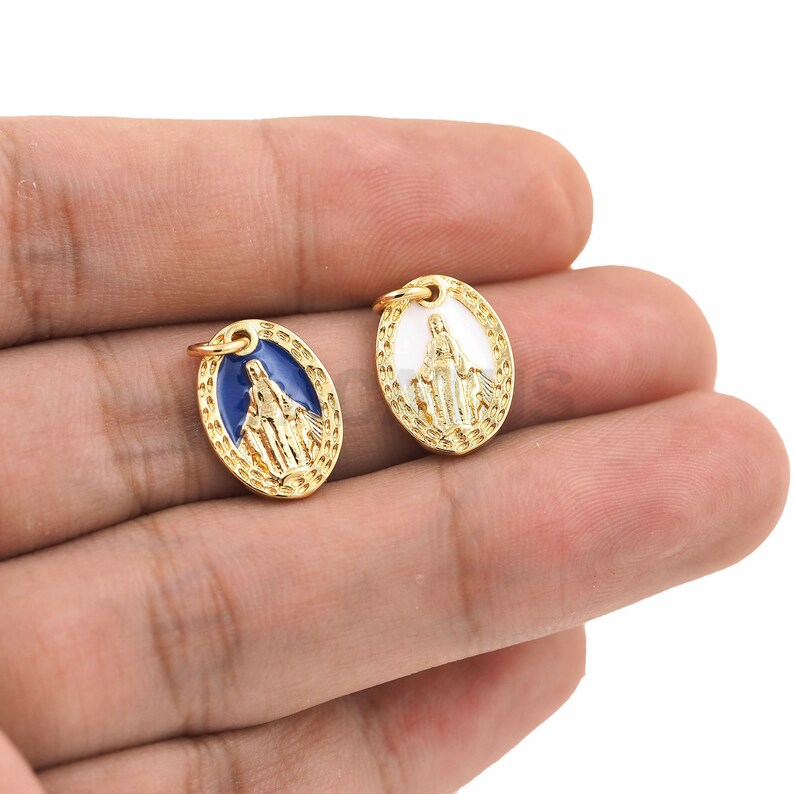 May include: Two gold-colored oval charms with a raised image of the Virgin Mary. One charm has a blue enamel background and the other has a white enamel background.