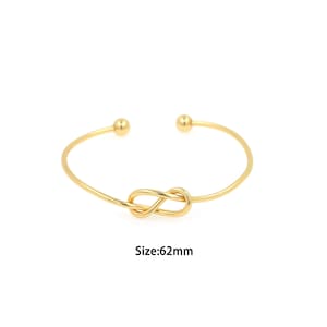 Puede incluir: Un brazalete dorado con un diseño de nudo. El brazalete tiene un diámetro de 62 mm.