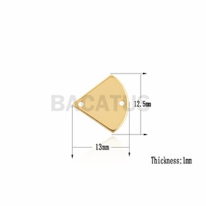 Può includere: Ciondolo triangolare in metallo dorato con due fori. Il ciondolo misura 12,5 mm di altezza e 13 mm di larghezza. Lo spessore è di 1 mm.