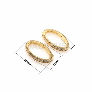 May include: Two gold oval-shaped clasps with clear cubic zirconia stones. The clasps are 1.55 inches long and 0.38 inches wide.