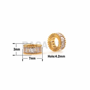 Puede incluir: Anillo dorado con piedras de circonita cúbica transparentes. El anillo mide 7 mm de diámetro y tiene un agujero de 4,2 mm.