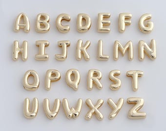 May include: A full set of gold-colored alphabet charms, each letter in a rounded, bubble-like font. The letters are arranged in rows, showcasing the entire English alphabet from A to Z. The charms have a shiny, metallic finish.