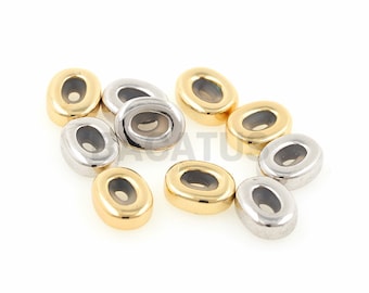 May include: A group of oval-shaped beads with a silver and gold finish. The beads have a hole in the centre and are arranged in a random pattern.