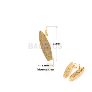Op de afbeelding: Goudkleurige surfplankbedel met heldere kristallen accenten. De bedel is 21 mm lang en 6,3 mm breed. De bedel is 3,3 mm dik.