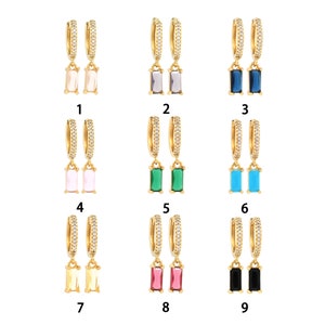 May include: Gold-tone hoop earrings with a row of small, clear stones. Each earring has a rectangular, colored stone pendant. The available colors are: light pink, gray, dark blue, green, light blue, yellow, red, and black.
