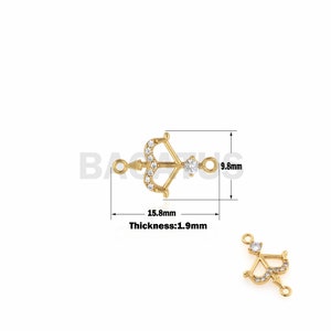 Può includere: Ciondolo dorato con un design a forma di arco e freccia, incrostato di strass trasparenti. Il ciondolo misura 15,8 mm di lunghezza e 9,8 mm di altezza. Spessore: 1,9 mm.