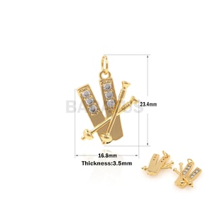 May include: Gold-tone charm pendant featuring a pair of skis with a crystal design and a pair of ski poles. The charm measures 1.68 inches in width and 2.34 inches in height. The charm is 3.5 mm thick.