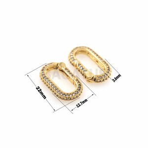 May include: Gold-toned oval-shaped connector with clear cubic zirconia stones. The connector measures 1.27 inches in length and 0.87 inches in width.