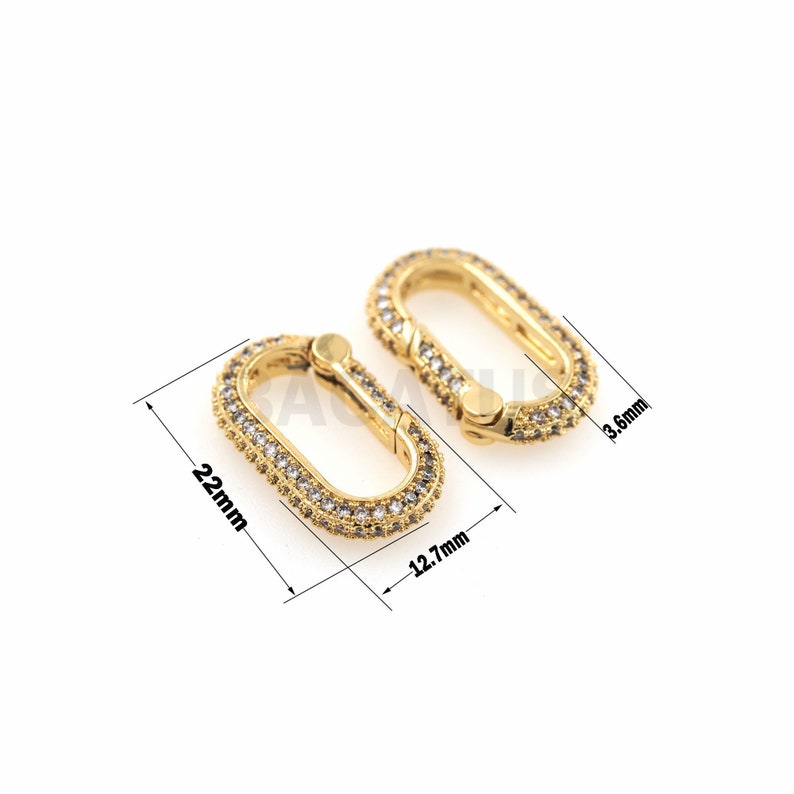 May include: Gold-toned oval-shaped connector with clear cubic zirconia stones. The connector measures 1.27 inches in length and 0.87 inches in width.