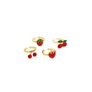 May include: Four adjustable rings with fruit designs. The rings feature gold-colored bands and are adorned with red strawberries and cherries with green leaves. The fruit designs are enameled with red and green colors.