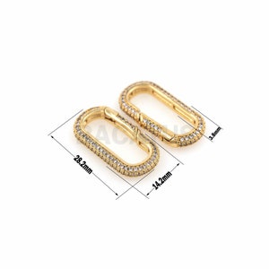 May include: Two gold-toned oval-shaped clasps with clear rhinestones. The clasps are 14.2 mm wide and 28.2 mm long.