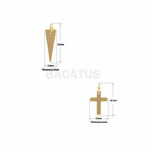 Op de afbeelding: Twee goudkleurige metalen bedels, een in de vorm van een driehoek en de andere in de vorm van een kruis. De driehoekbedel is 5,2 cm hoog en 1,5 cm breed. De kruisbedel is 3,8 cm hoog en 2,3 cm breed. Beide bedels hebben een dikte van 0,4 cm.