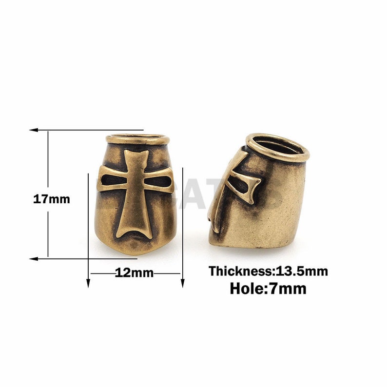 以下が含まれることがあります： 十字架のデザインの真鍮製のチャーム。チャームの高さは17mm、幅は12mmです。穴の直径は7mmです。