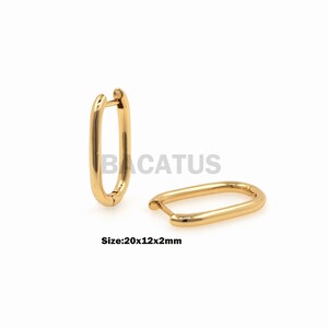 May include: Two gold-colored oval hoop earrings. The earrings are shown on a white background. The size is 20x12x2mm. The earrings have a simple, polished design. The earrings are a classic jewelry item.