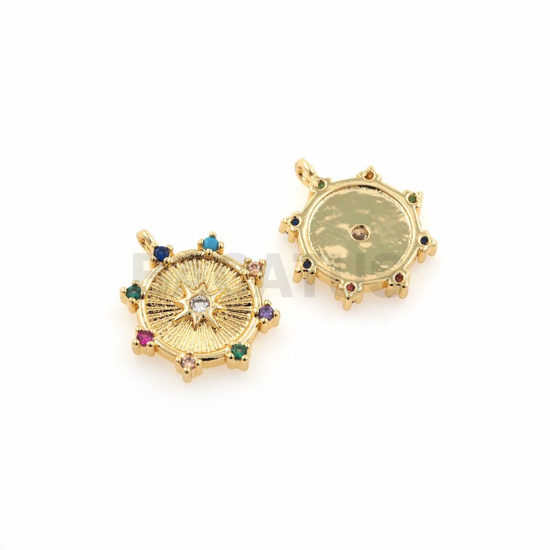 K&ouml;nnte beinhalten: Zwei goldfarbene Anh&auml;nger mit kreisf&ouml;rmigem Design. Ein Anh&auml;nger zeigt ein Sternburst-Design mit bunten Edelsteinen am Rand. Der andere Anh&auml;nger ist schlicht mit bunten Edelsteinen am Rand.