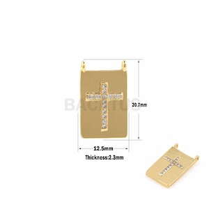 May include: Gold-tone pendant with a clear crystal cross design. The pendant is rectangular and measures 1.25 inches wide by 2.07 inches tall. The thickness is 0.23 inches.