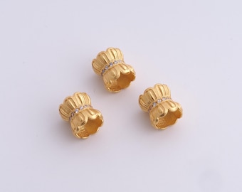 May include: Three gold-colored, decorative beads with a floral design. Each bead features a band of small, clear stones. The beads are arranged on a white background, showcasing their intricate details and metallic sheen. Ideal for jewelry making.