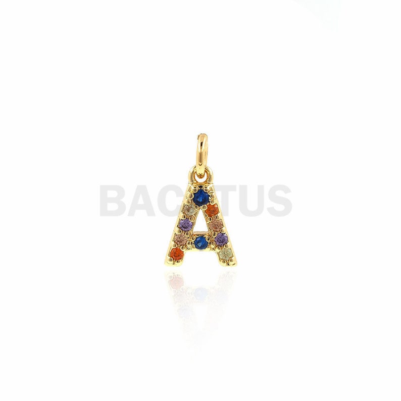 Puede incluir: Encanto de letra A de oro con piedras preciosas de colores. El encanto es un colgante para un collar o una pulsera.