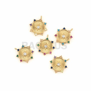 K&ouml;nnte beinhalten: Vier goldfarbene Anh&auml;nger mit einem Sternburst-Design und einem klaren Kristall in der Mitte. Jeder Anh&auml;nger ist von einem Kreis aus bunten Edelsteinen umgeben.