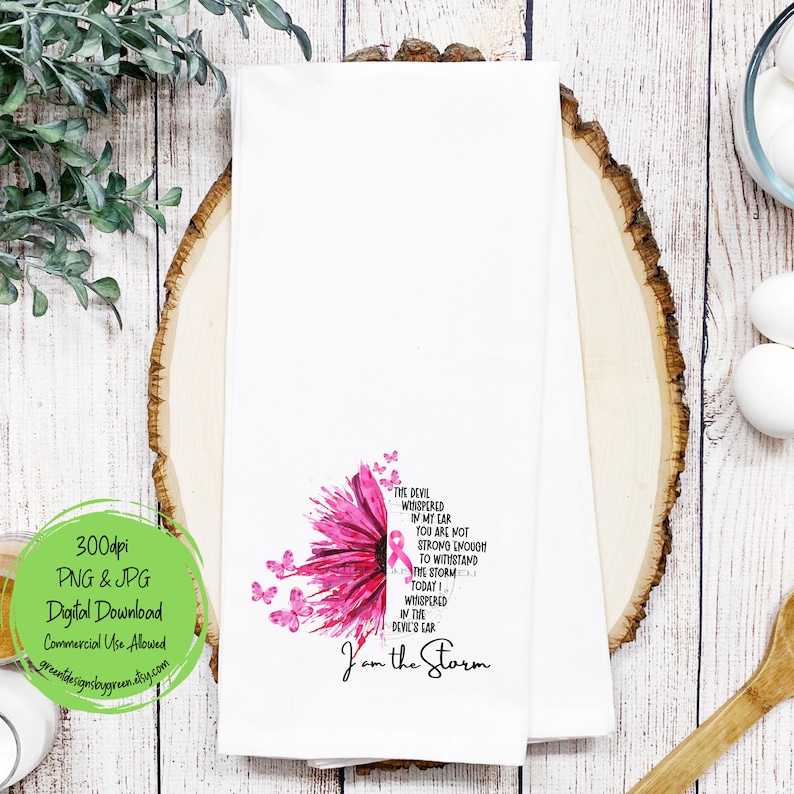May include: A white kitchen towel with a pink watercolor flower design and the text "The devil whispered in my car you are not strong enough to withstand the storm today I whispered in the devil's ear I am the storm".