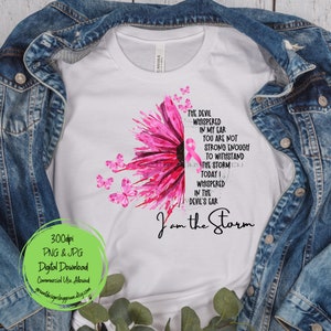 May include: A white t-shirt with a pink watercolor flower design and butterflies. The text "The devil whispered in my ear you are not strong enough to withstand the storm today I whispered in the devil's ear I am the storm" is printed on the shirt.