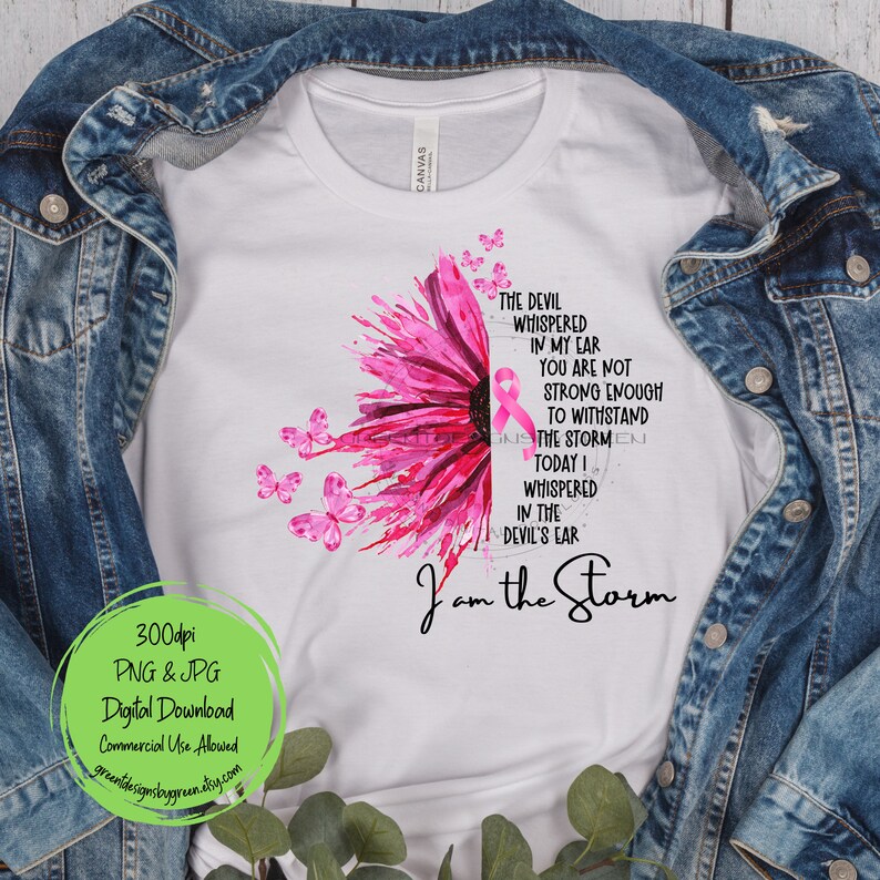 May include: A white t-shirt with a pink watercolor flower design and butterflies. The text "The devil whispered in my ear you are not strong enough to withstand the storm today I whispered in the devil's ear I am the storm" is printed on the shirt.
