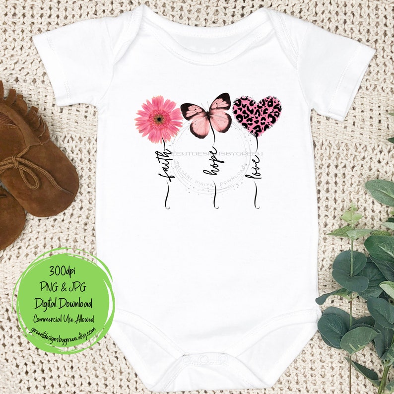 May include: White baby bodysuit with a pink butterfly, a pink flower, and a pink leopard print heart. The words "faith", "hope", and "love" are written below the design.