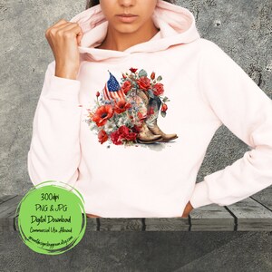 May include: A pink hoodie with a design of a pair of cowboy boots, red roses, and an American flag. The design is in a watercolor style.