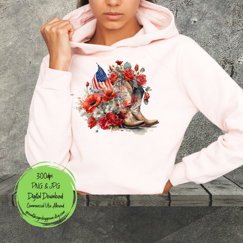 May include: A pink hoodie with a design of a pair of cowboy boots, red roses, and an American flag. The design is in a watercolor style.