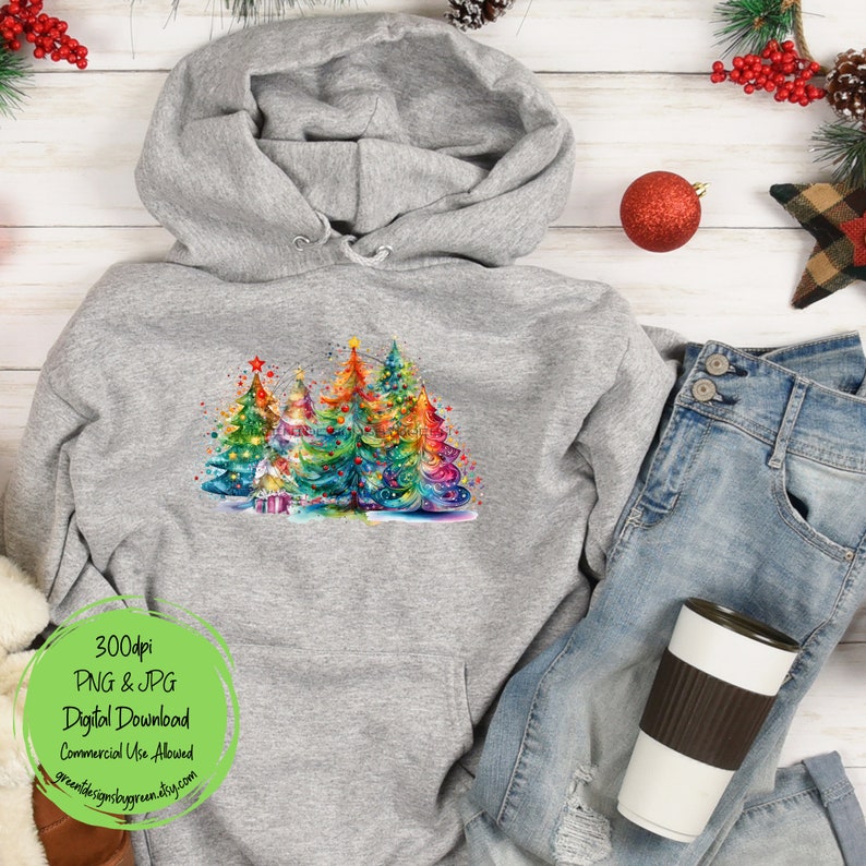 May include: A gray hoodie with a colorful watercolor design of Christmas trees with lights and ornaments. The design is centered on the front of the hoodie.