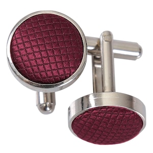 May include: A pair of silver cufflinks with a burgundy patterned fabric insert.