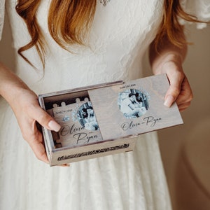 May include: A wooden box with a hinged lid, decorated with a floral design and a photo of a couple. The box is engraved with the names "Olivia and Ryan" and the date "June 10, 2023".