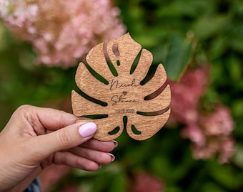 May include: A wooden leaf-shaped wedding favor with the names "Nicole" and "Steven" and the date "03.12.2022" engraved on it.