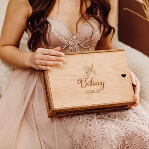 May include: A wooden box with a floral design and the name Bethany engraved on it. The box also has the date 12.21.23 engraved on it.