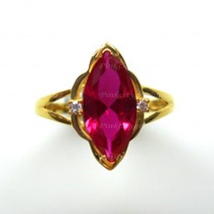 Peut inclure: Une bague en or avec une grande pierre précieuse rose vif de forme marquise. La bague a un design délicat et complexe avec de petites pierres précieuses claires de chaque côté de la pierre principale.