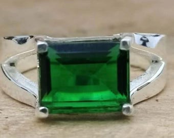 May include: A silver ring with a large, emerald green gemstone set in a square shape.