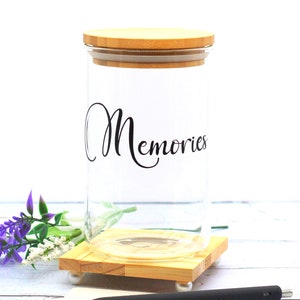 May include: A glass jar with a bamboo lid and base. The jar is labeled "Memories".