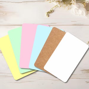 May include: Six blank cards in different colors: yellow, light green, pink, light blue, brown, and white. The cards are arranged in a fan shape on a light wood surface.