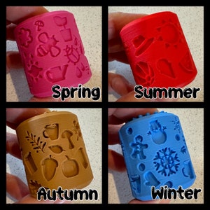 May include: Four colourful rubber stamps with different designs representing the four seasons: spring, summer, autumn, and winter. Each stamp features a unique pattern of icons and symbols related to the corresponding season.