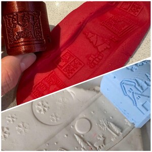 May include: Two rolling pins with different designs. One is red with a Christmas tree, house, and snowflake design. The other is blue with a house and tree design. Both are used to create impressions in red and white play dough.