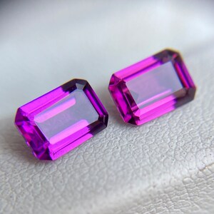 May include: Two purple gemstone earrings with a rectangular emerald cut.