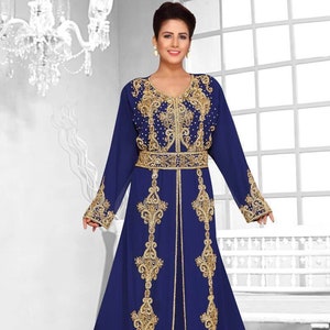 May include: A long, flowing royal blue kaftan with intricate gold embroidery and beading. The kaftan has a V-neckline and long sleeves. It is belted at the waist.